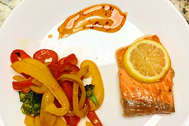 baked salmon filet with a lemon sauce and sauteed vegetables
